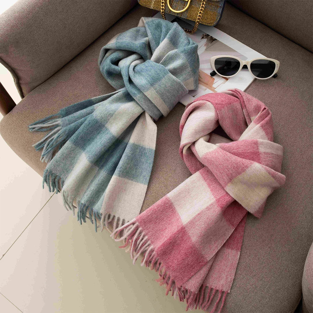 Blue and pink checked wool scarves knotted beside white sunglasses