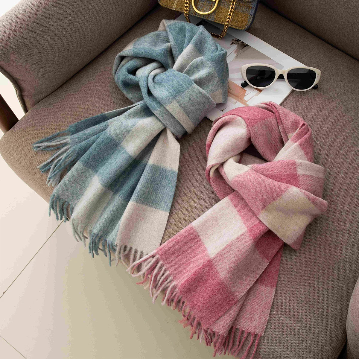 Blue and pink checked wool scarves knotted beside white sunglasses