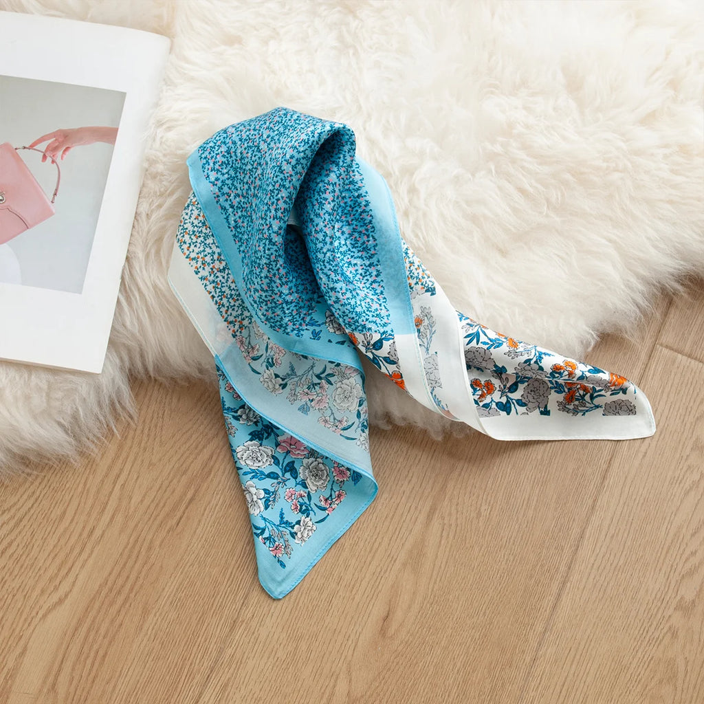 Blue floral silk scarf styled on soft surface