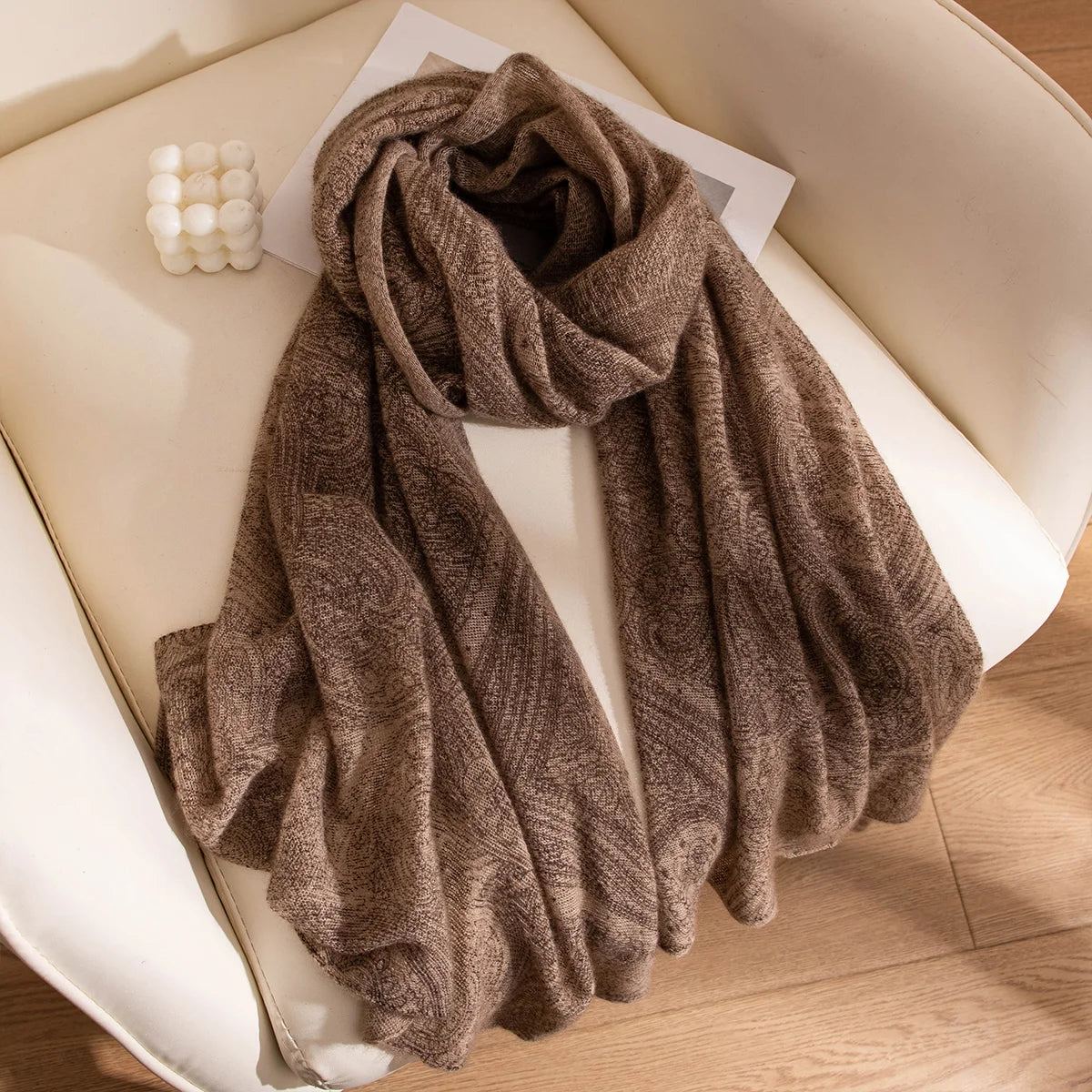 Brown open weave cashmere scarf draped across a cream chair