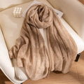 Camel cashmere scarf gathered in flowing folds on chair
