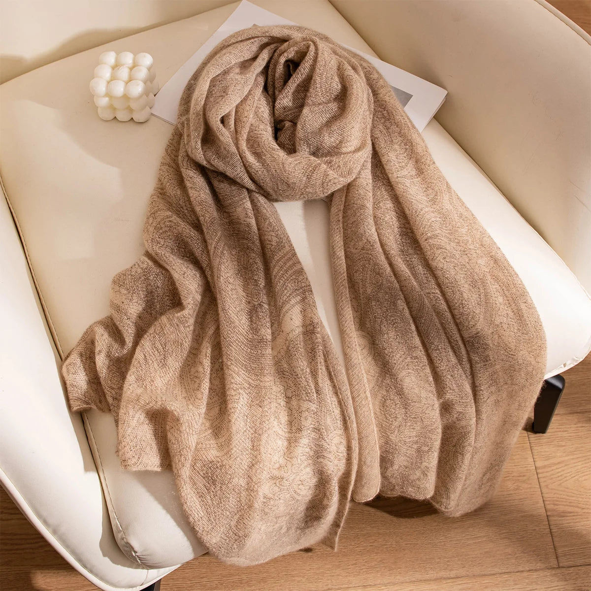 Camel cashmere scarf gathered in flowing folds on chair