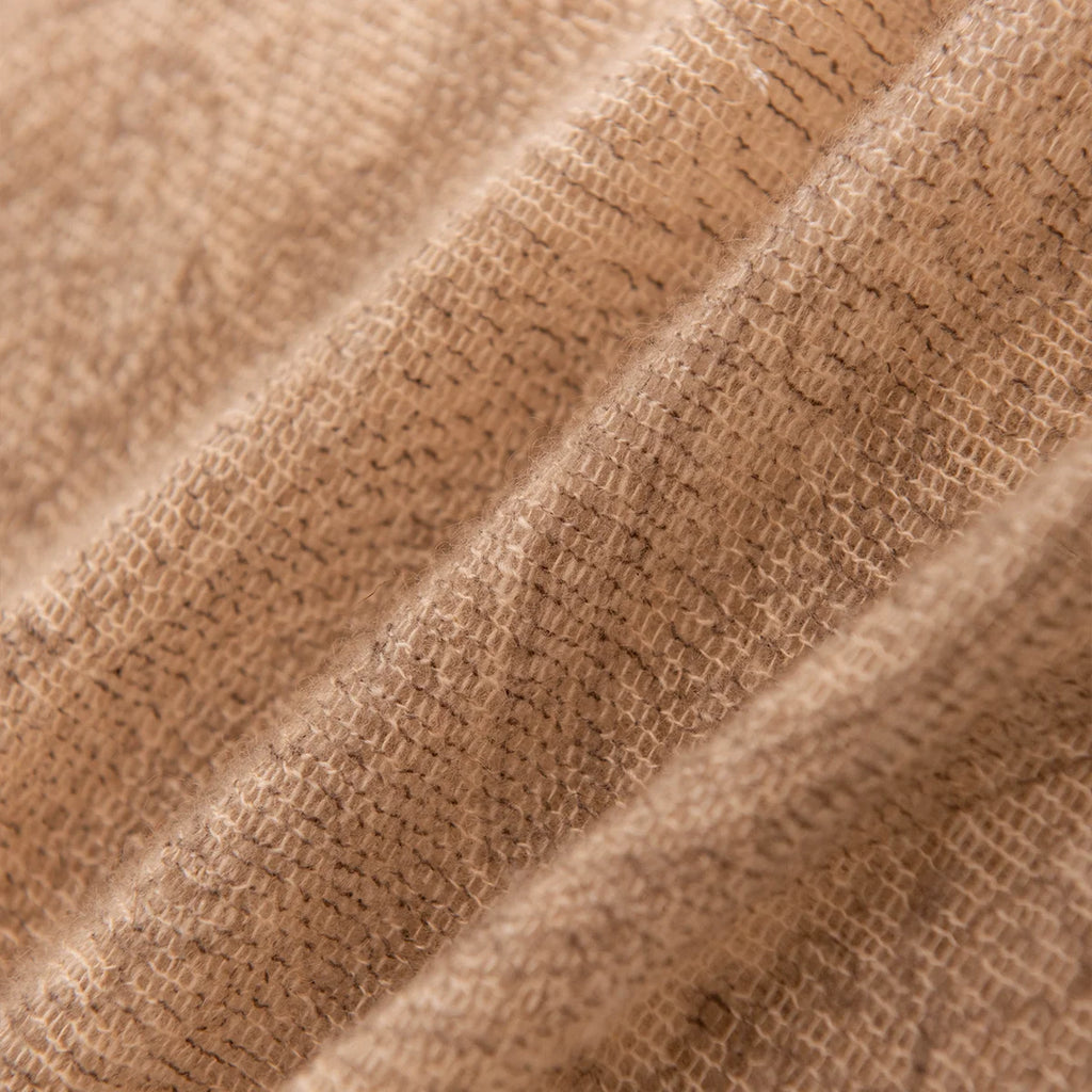 Close view of open woven texture across camel folds
