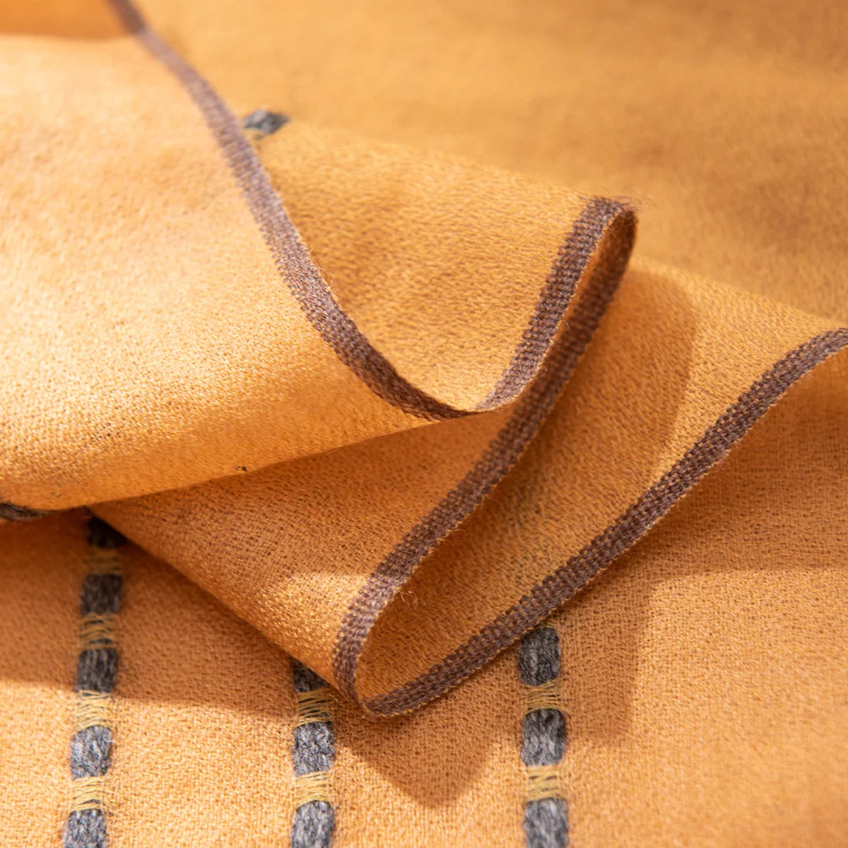 Contrasting running stitches beside a narrow bound wool scarf edge