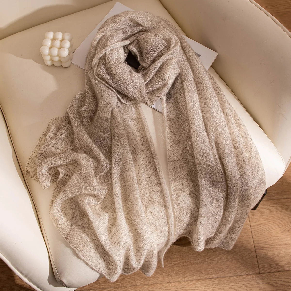 Cream open weave cashmere scarf loosely arranged on a chair