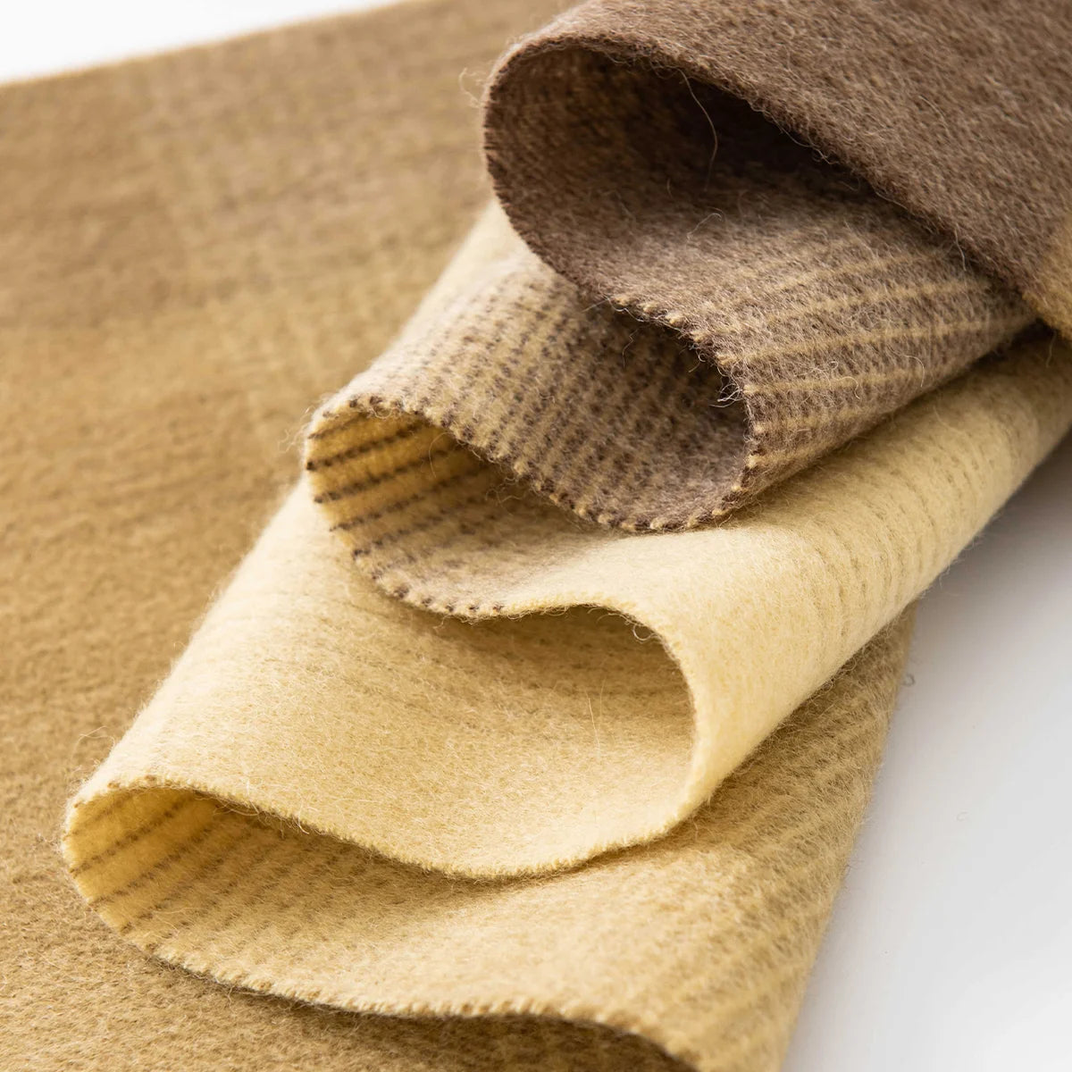 Curled mustard brown fabric revealing fine underlying woven checks