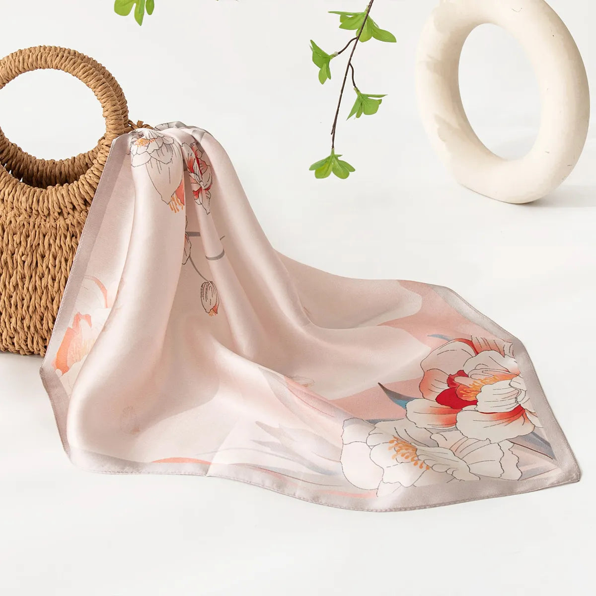 Draped light pink floral silk scarf near woven bag