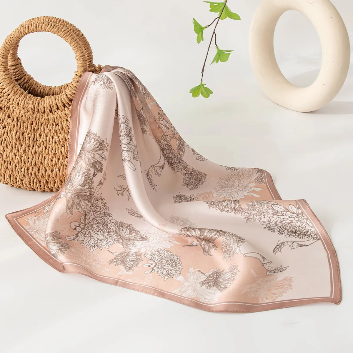 Draped pink floral silk scarf near woven straw bag