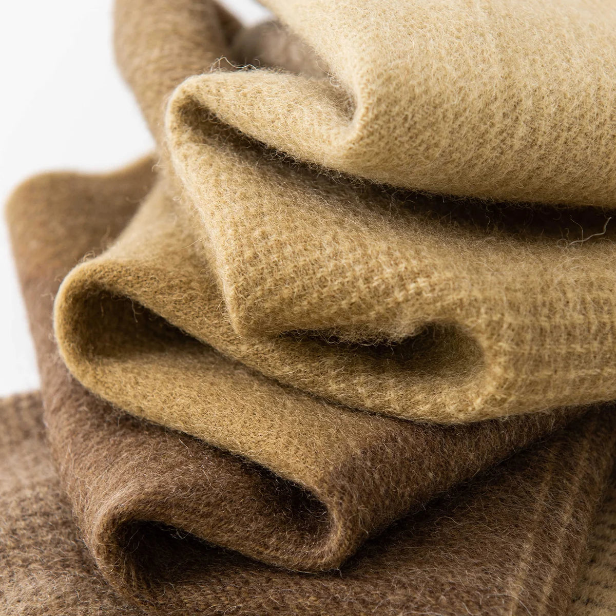 Folded mustard and brown wool scarf layers showing brushed texture