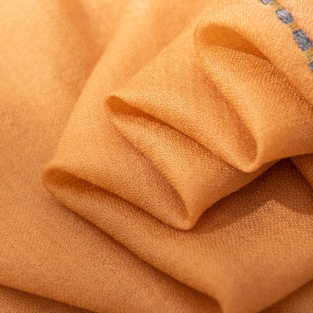 Folded mustard wool scarf layers showing the fine woven surface