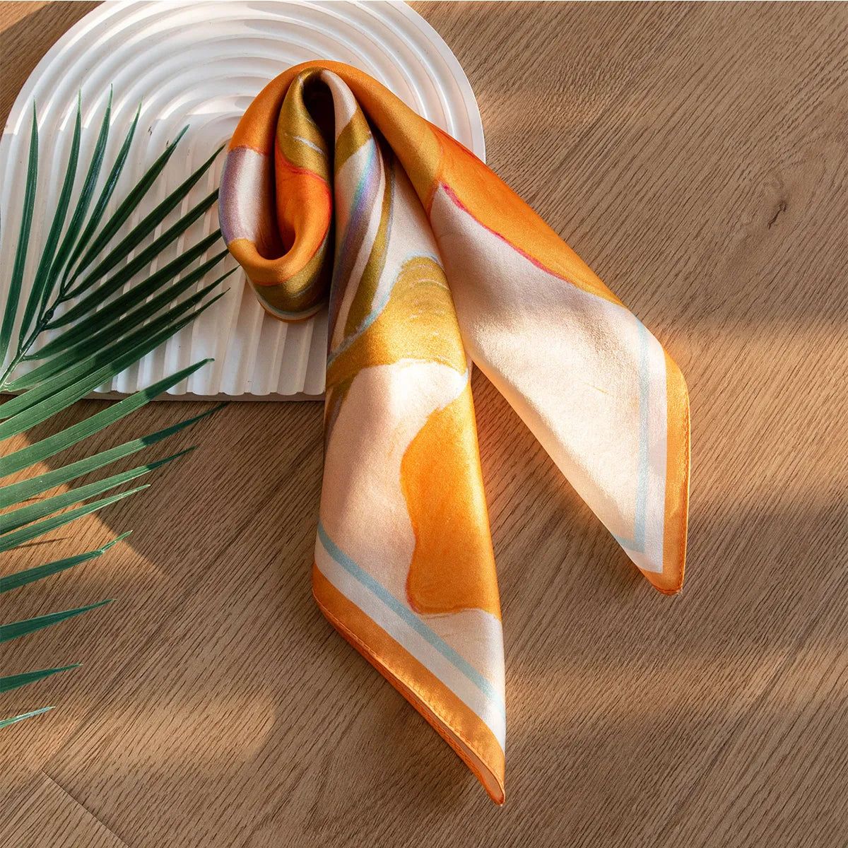 Folded orange and peach silk scarf on tray