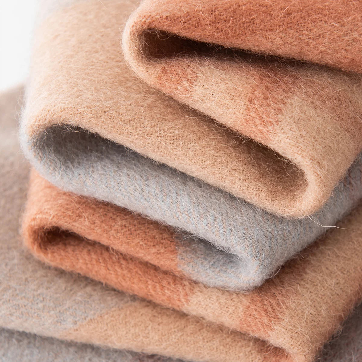 Folded peach and pale blue wool scarf layers showing texture