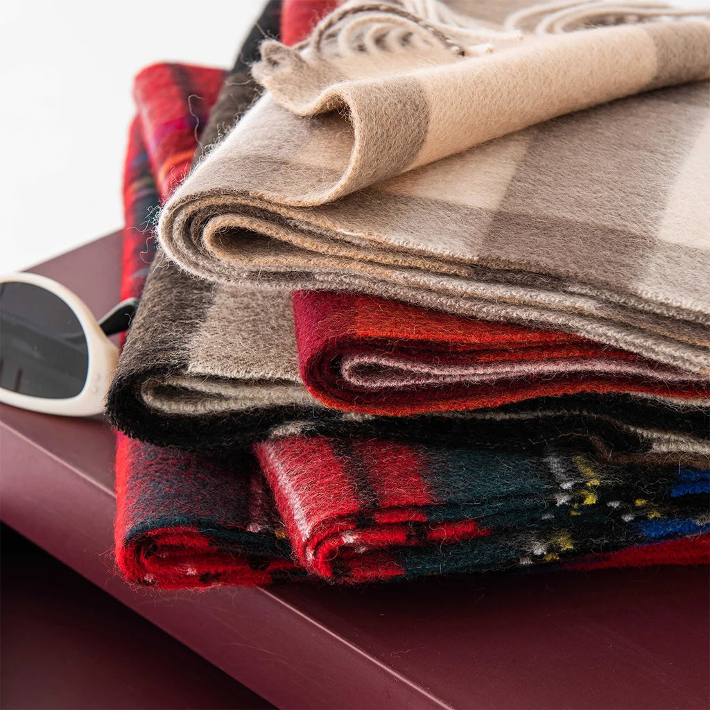 Folded plaid wool scarves stacked with beige version on top