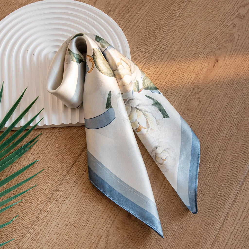 Folded white silk scarf with blue border and floral pattern