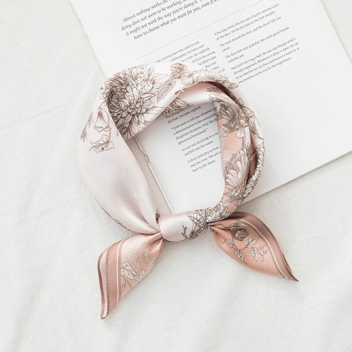 Knotted pink silk scarf with botanical print on book