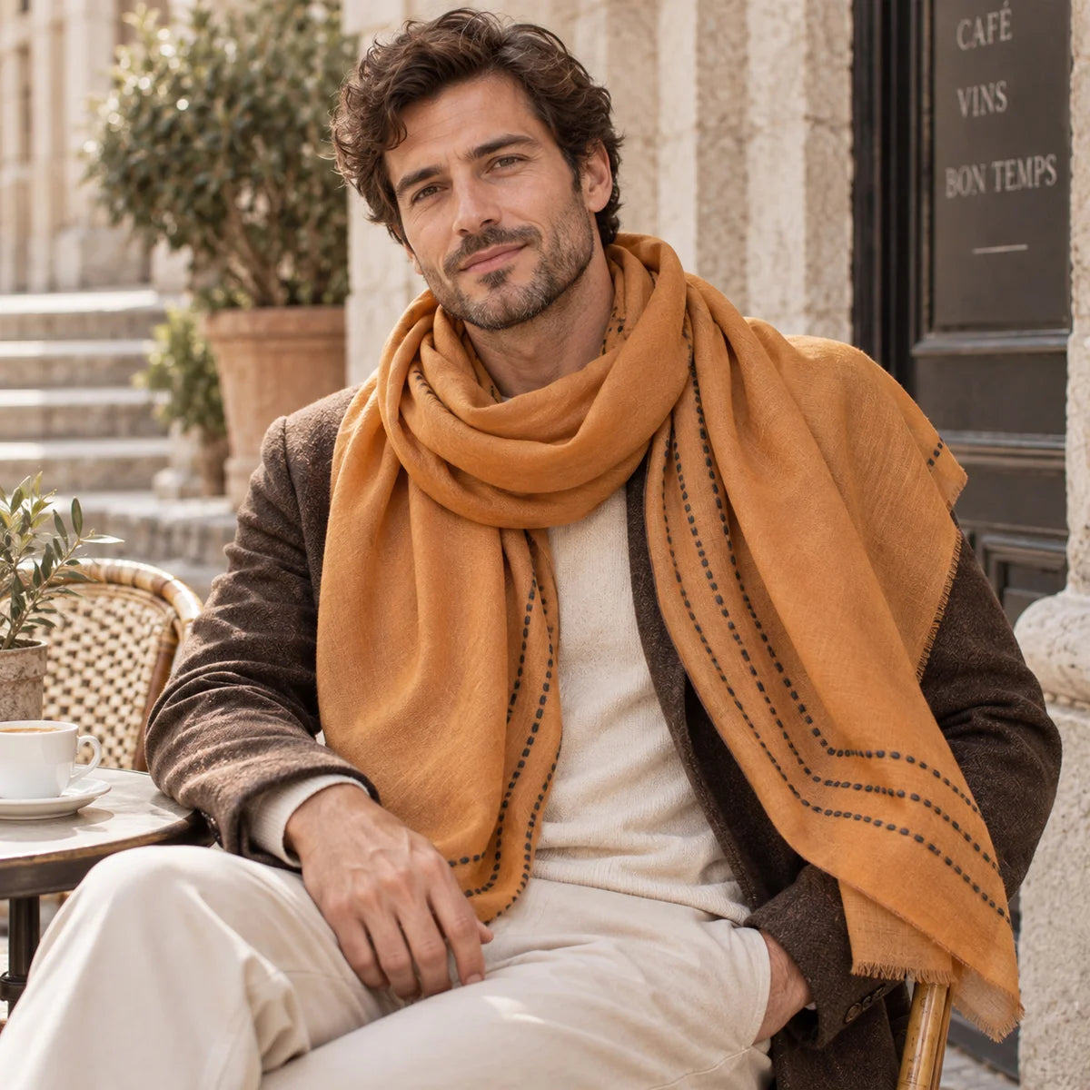 Man wearing mustard bordered wool scarf while seated outdoors
