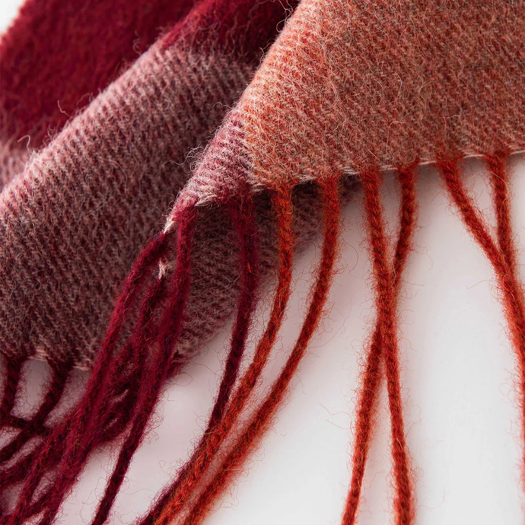 Mixed rust and burgundy fringe beneath the checked edge