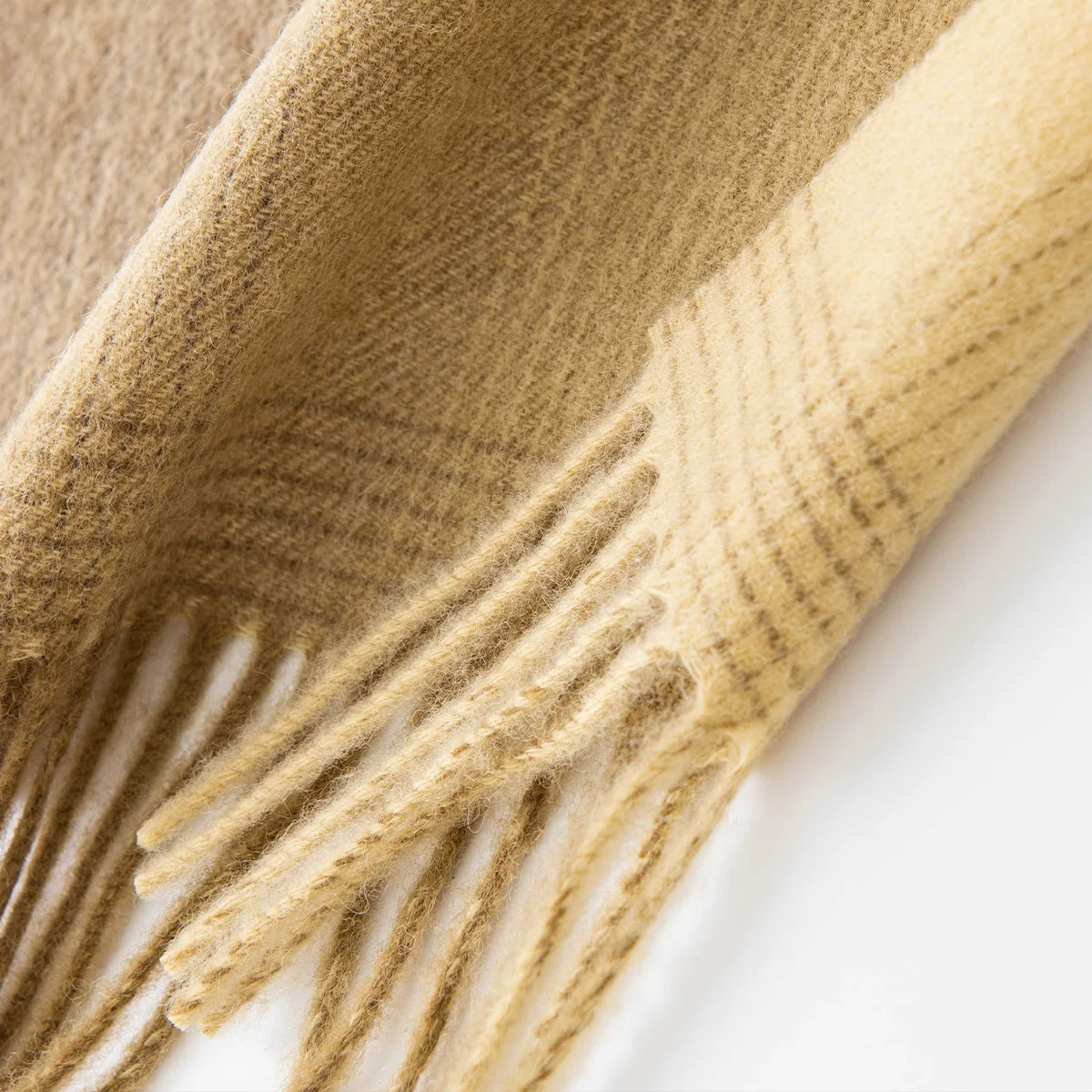 Mustard fringe beneath fine checks along the wool scarf edge