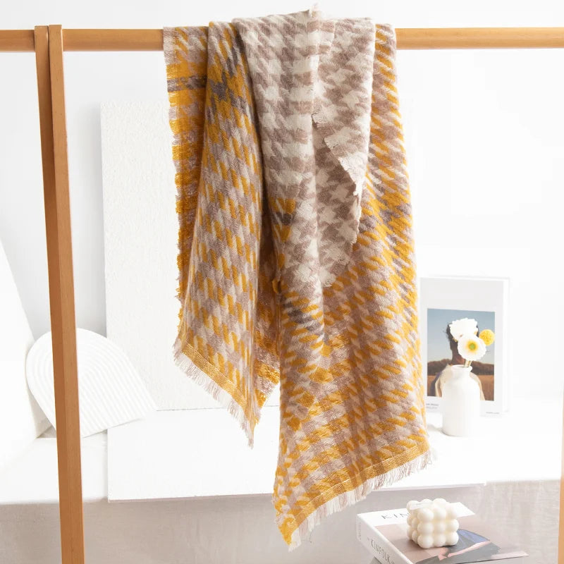 Mustard houndstooth wool scarf hanging over a wooden rail
