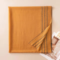 Mustard wool scarf folded to reveal rows of contrasting stitches