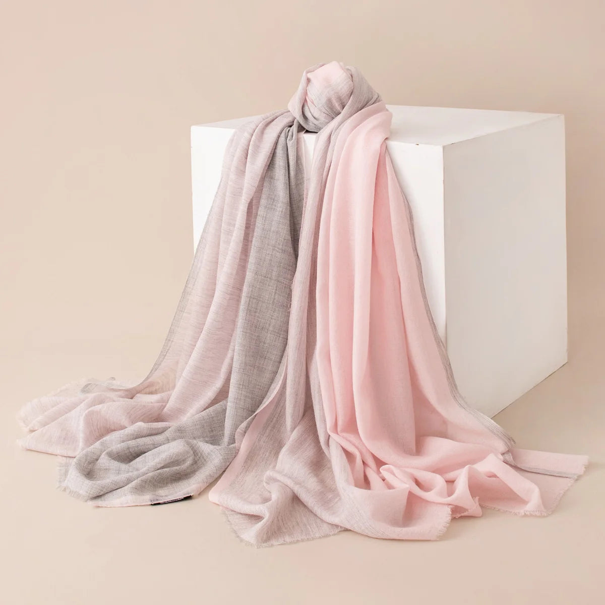 Pale pink gray wool scarf draped across white display block