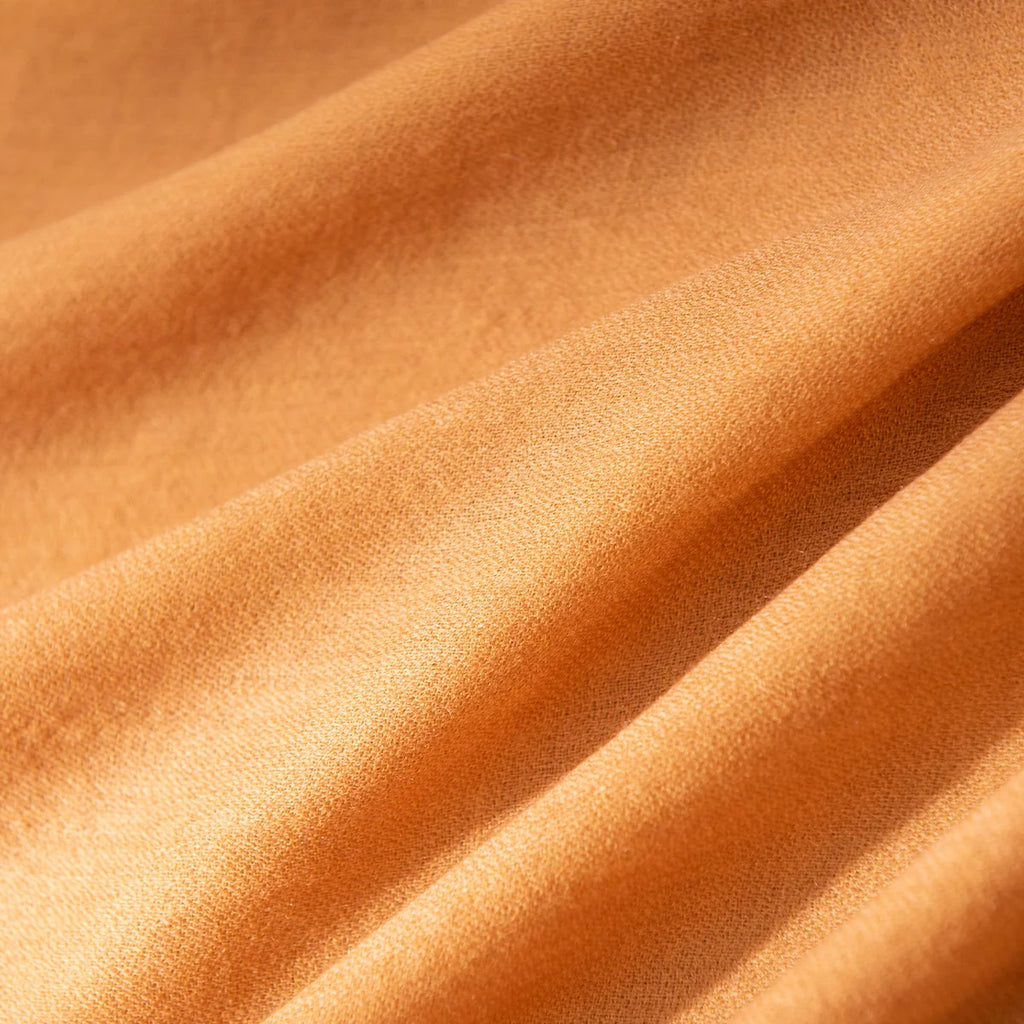 Plain mustard fabric revealing fine weave across flowing folds