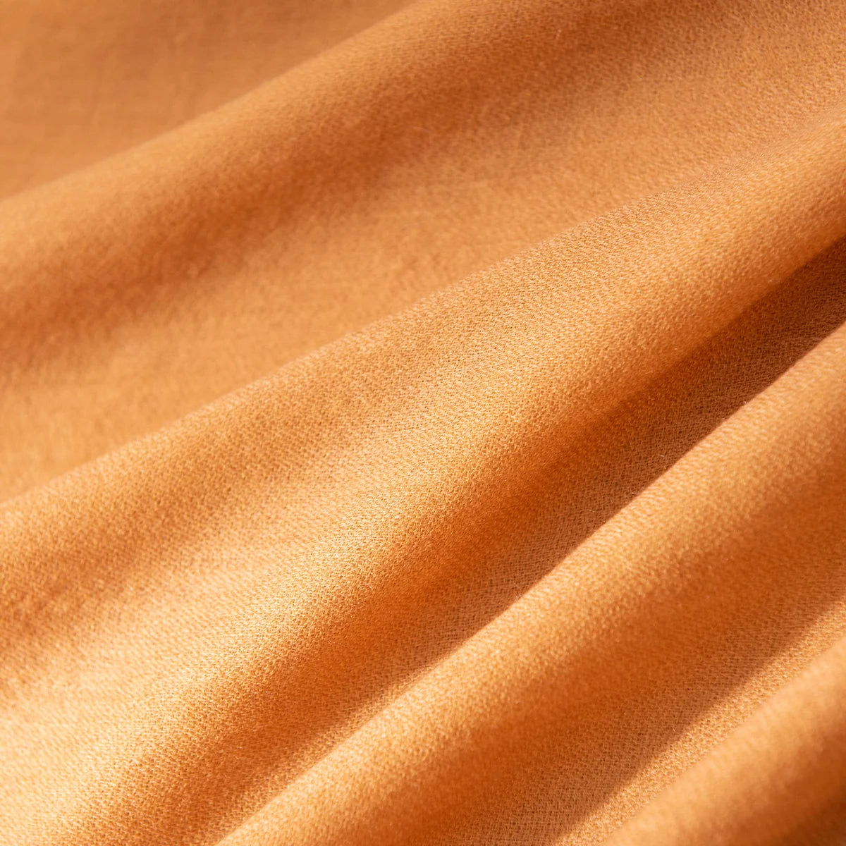 Plain mustard fabric revealing fine weave across flowing folds