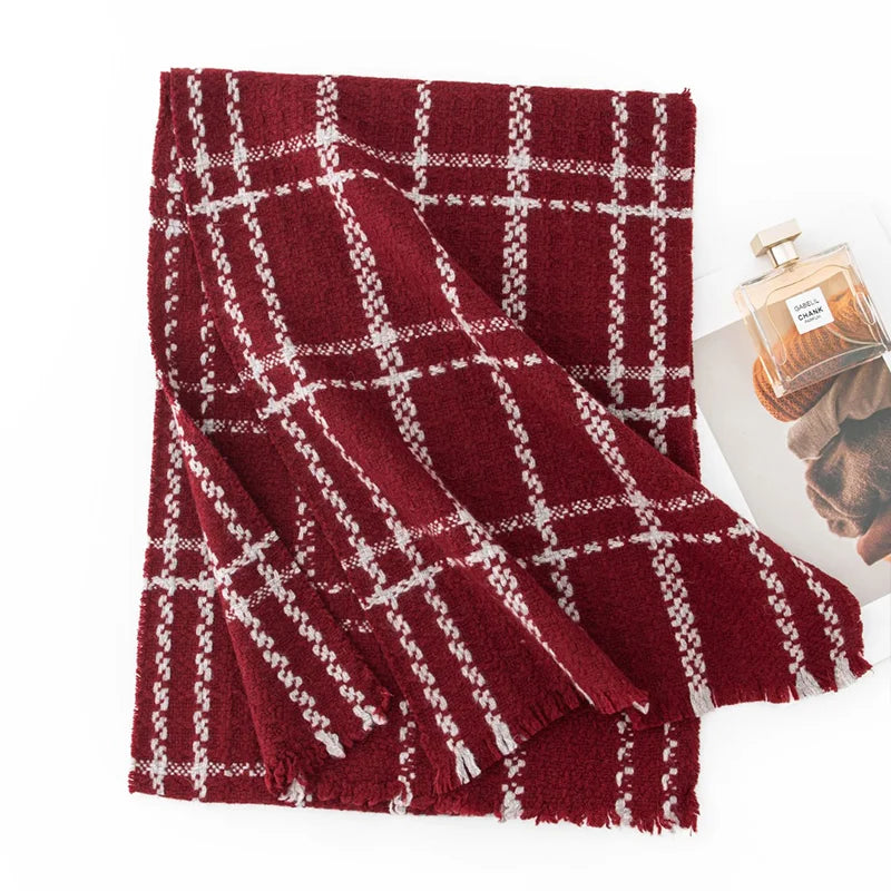 Red cream grid wool scarf folded beside a perfume bottle