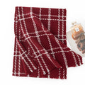 Red cream grid wool scarf folded beside a perfume bottle