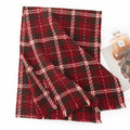 Red tartan wool scarf folded beside a small perfume bottle
