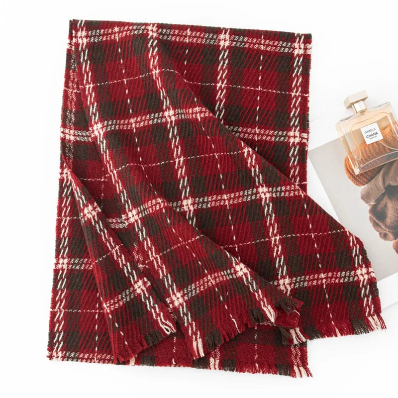 Red tartan wool scarf folded beside a small perfume bottle