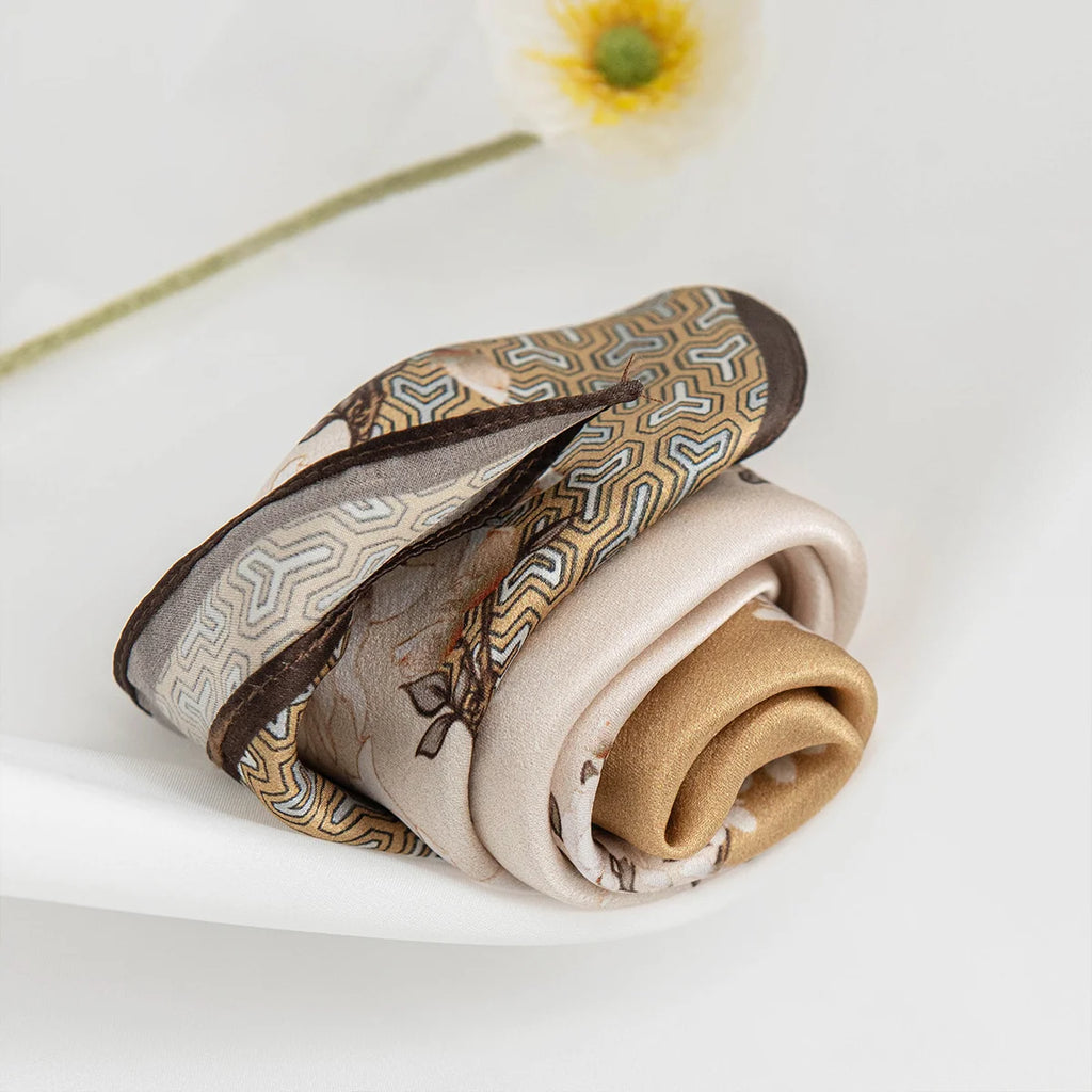 Rolled beige floral Silk Square Scarf on table