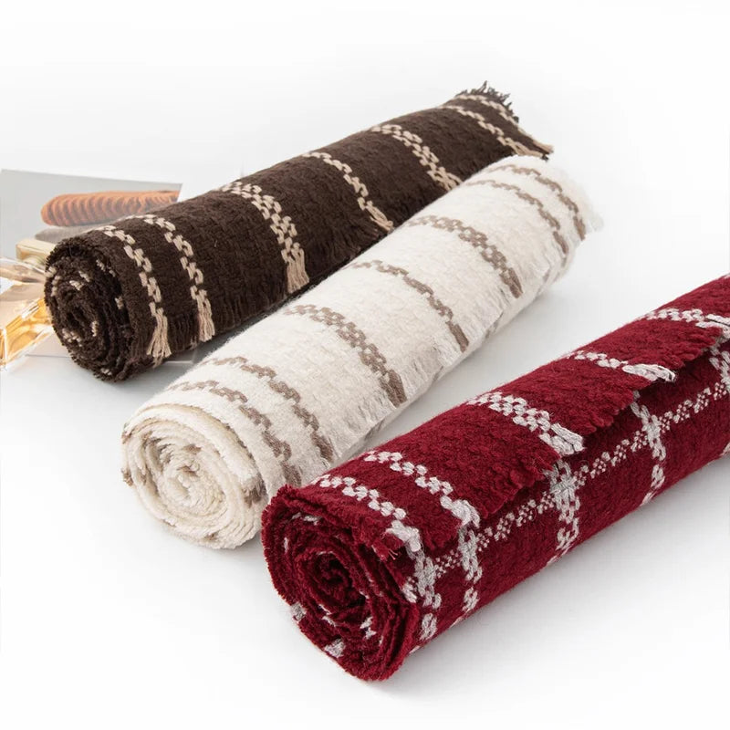 Rolled brown cream and red checked wool scarves on white