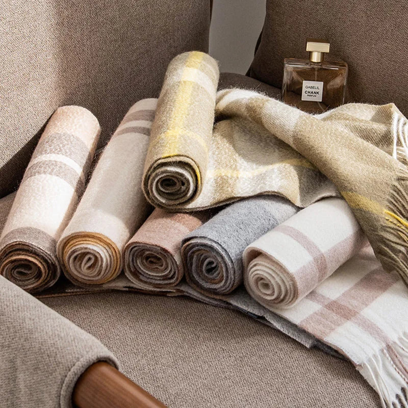 Rolled checked cashmere scarves beside a perfume bottle on chair