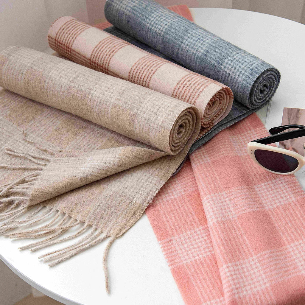 Rolled pastel checked wool scarves arranged beside a pink version