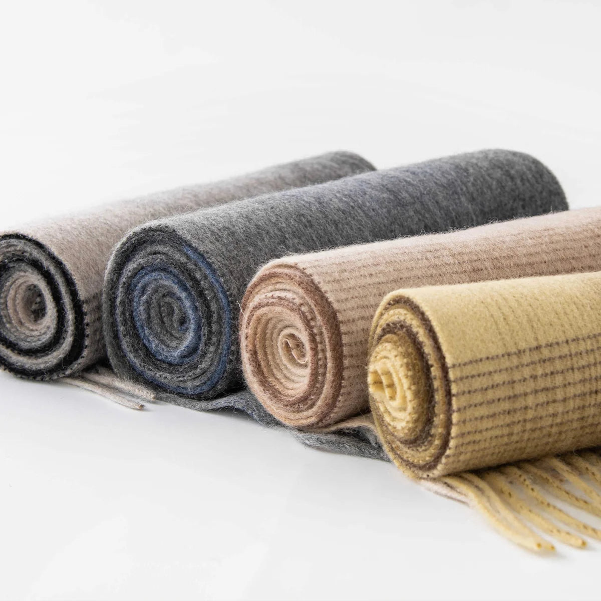 Rolled wool scarves displaying gray blue beige and mustard shades