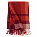 Rust and burgundy checked wool scarf beside a cream handbag