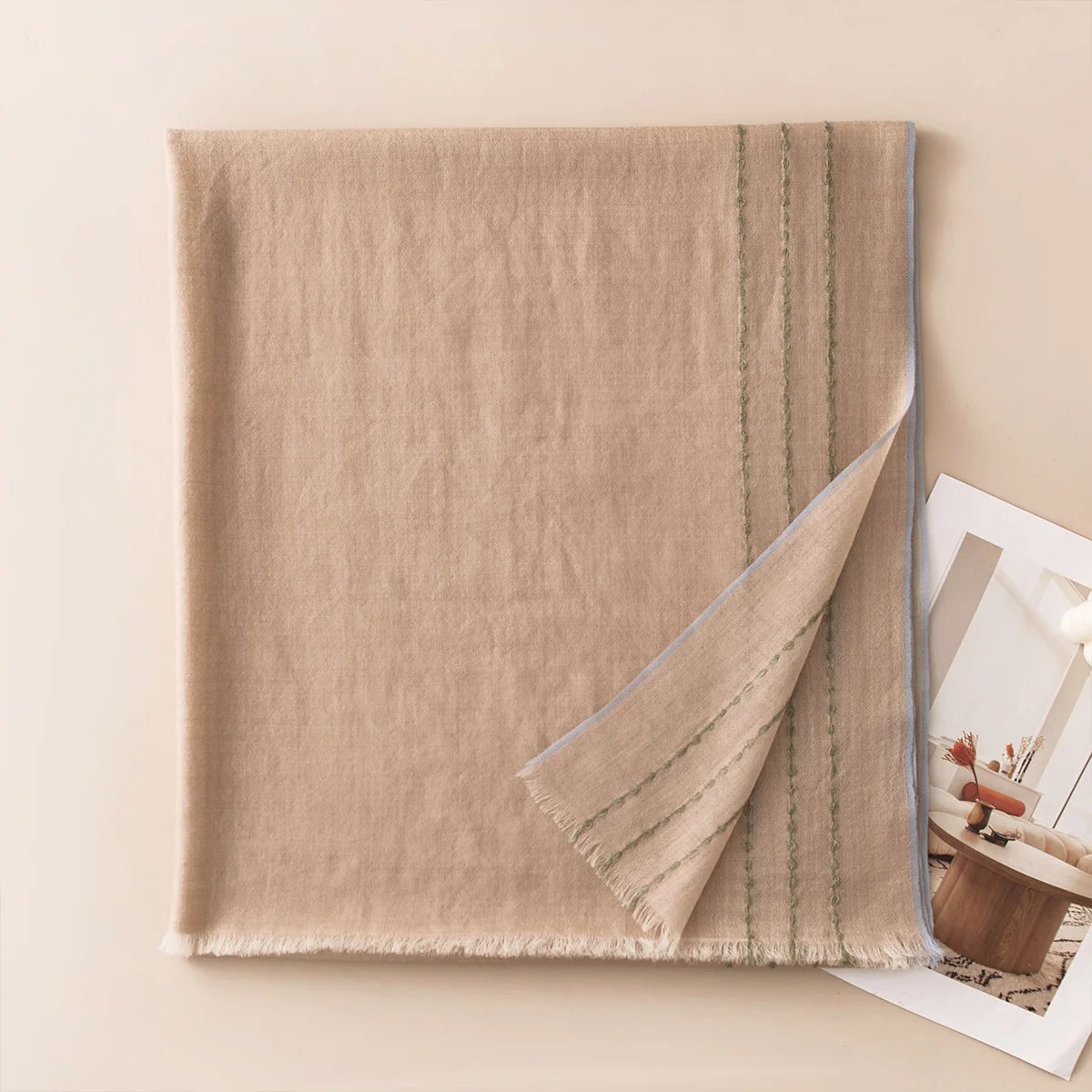 Taupe wool scarf with blue stitched border on neutral backdrop