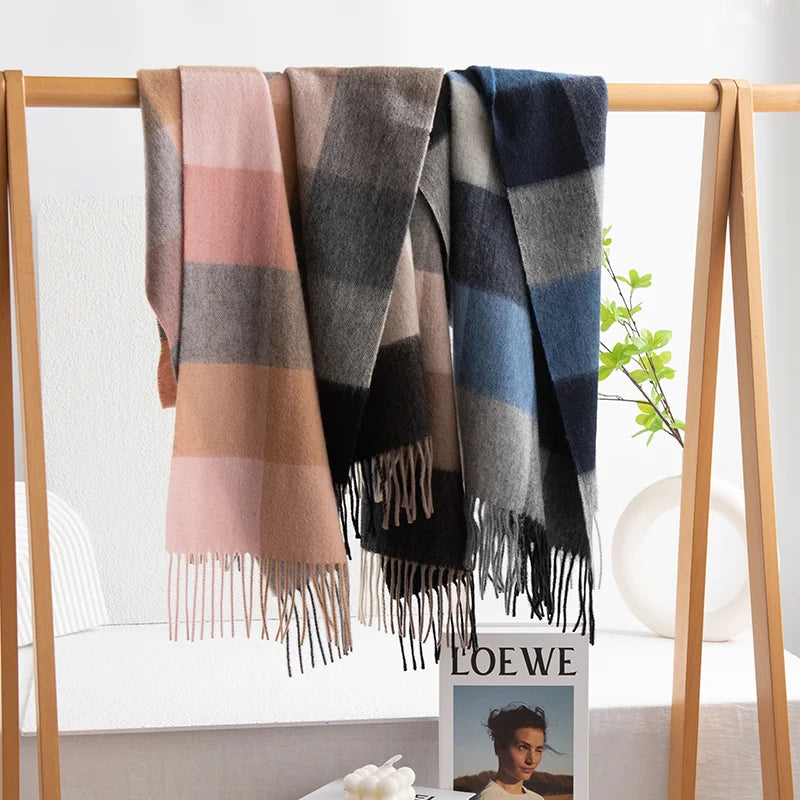 Three color block scarves hanging from a wooden rail