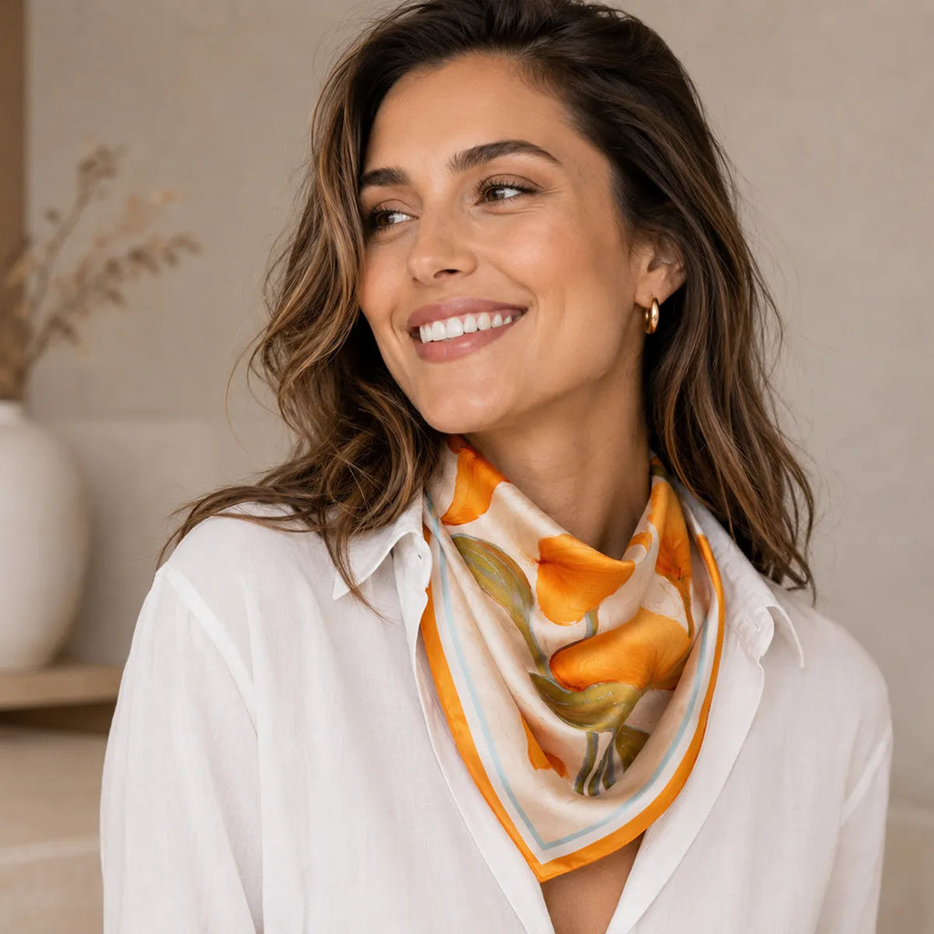 Woman in white shirt, orange floral scarf with light blue and orange border, draped