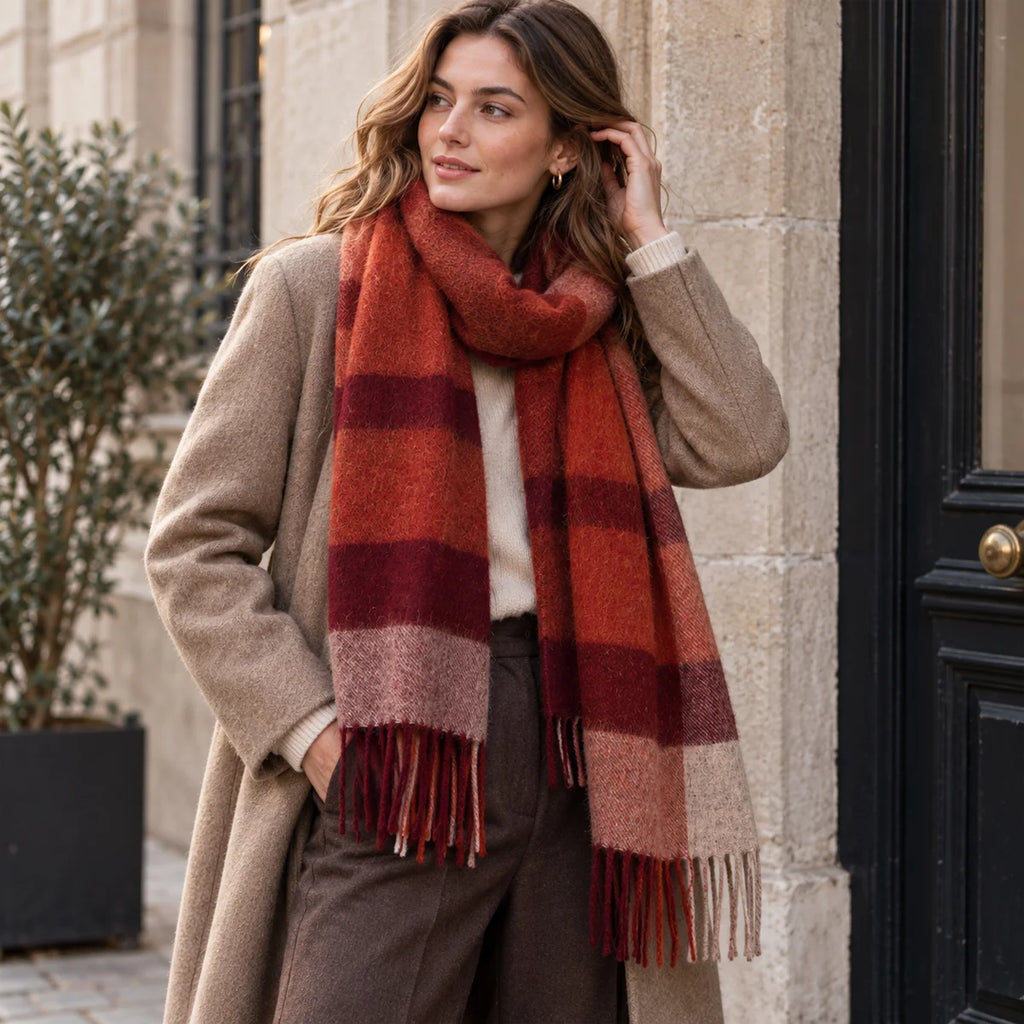 Woman wearing rust checked wool scarf beside a stone doorway