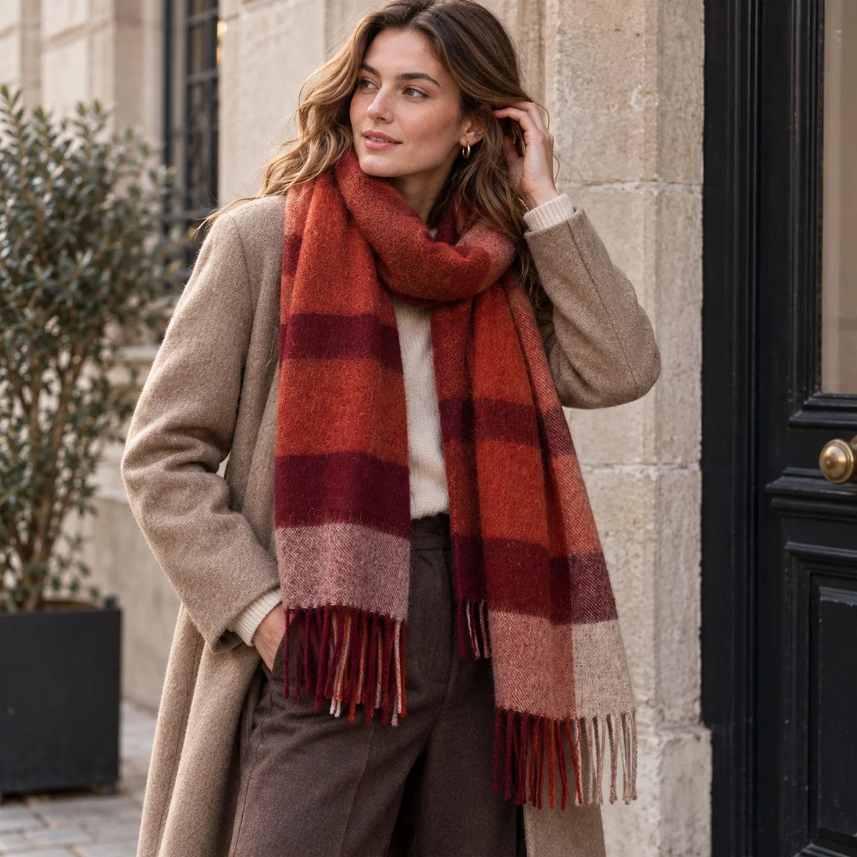 Woman wearing rust checked wool scarf beside a stone doorway