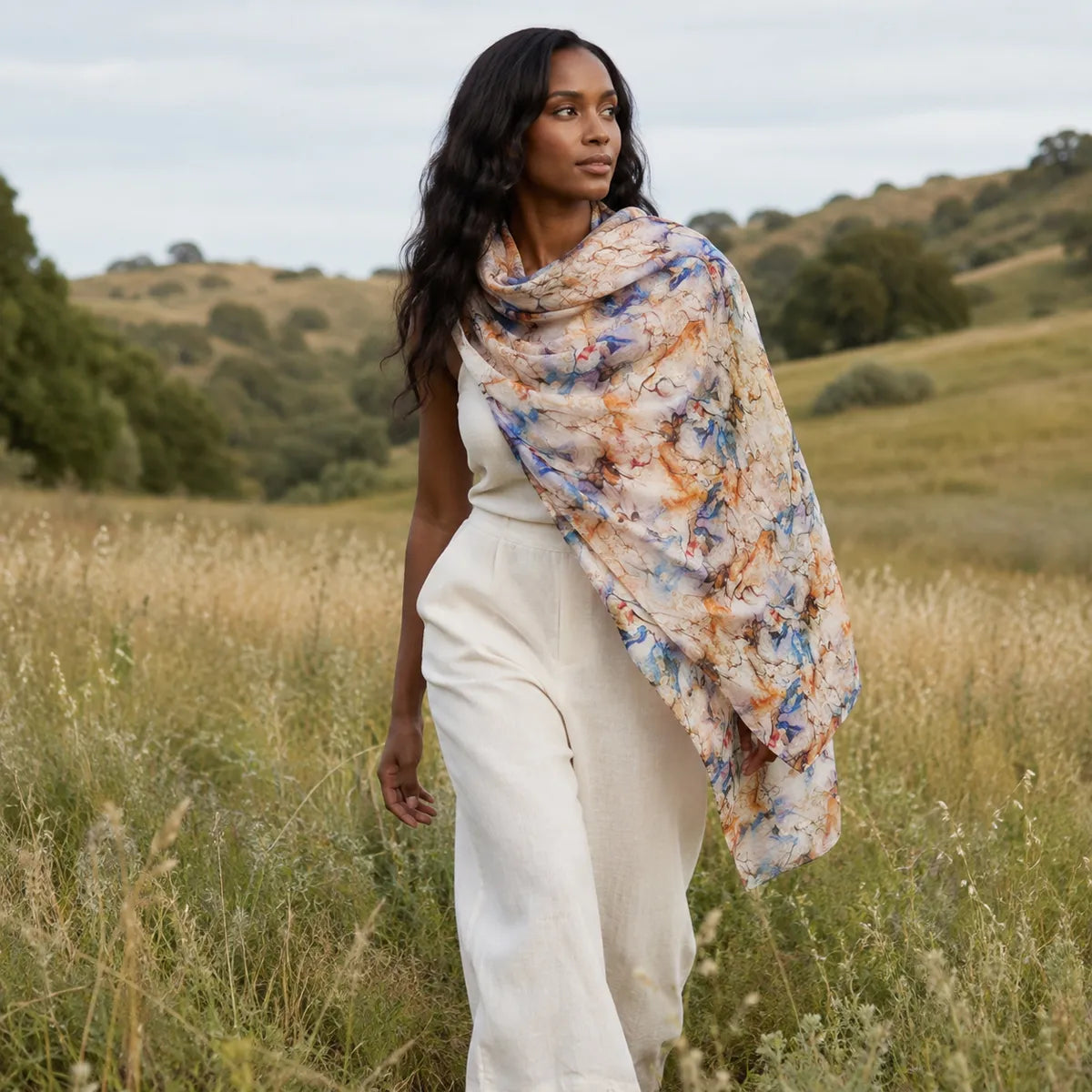 Woman wearing watercolor silk shawl in meadow